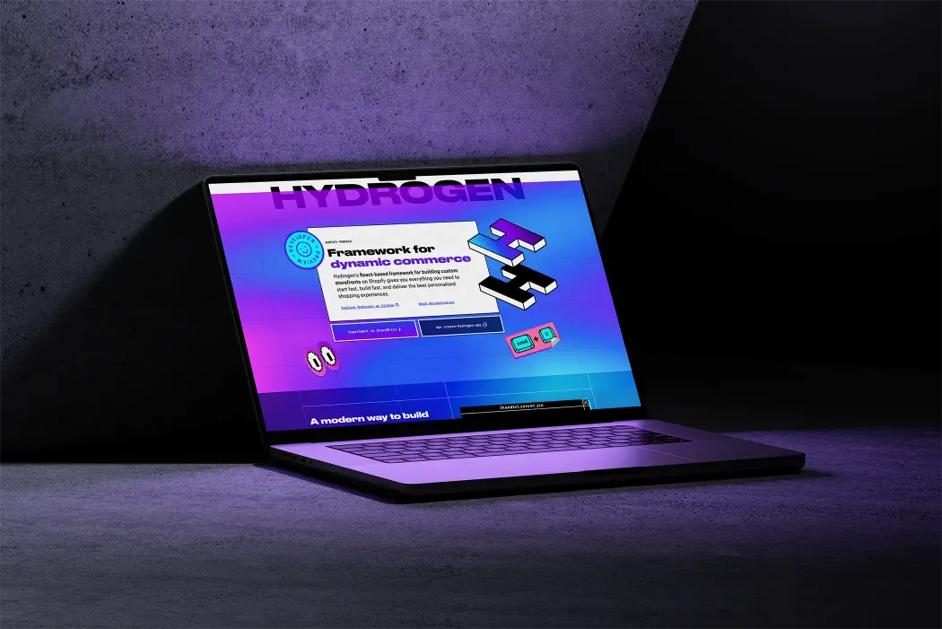 Laptop displaying a webpage titled 'Hydrogen,' featuring a vibrant, colorful design promoting a framework for dynamic commerce, set against a dark, textured background.