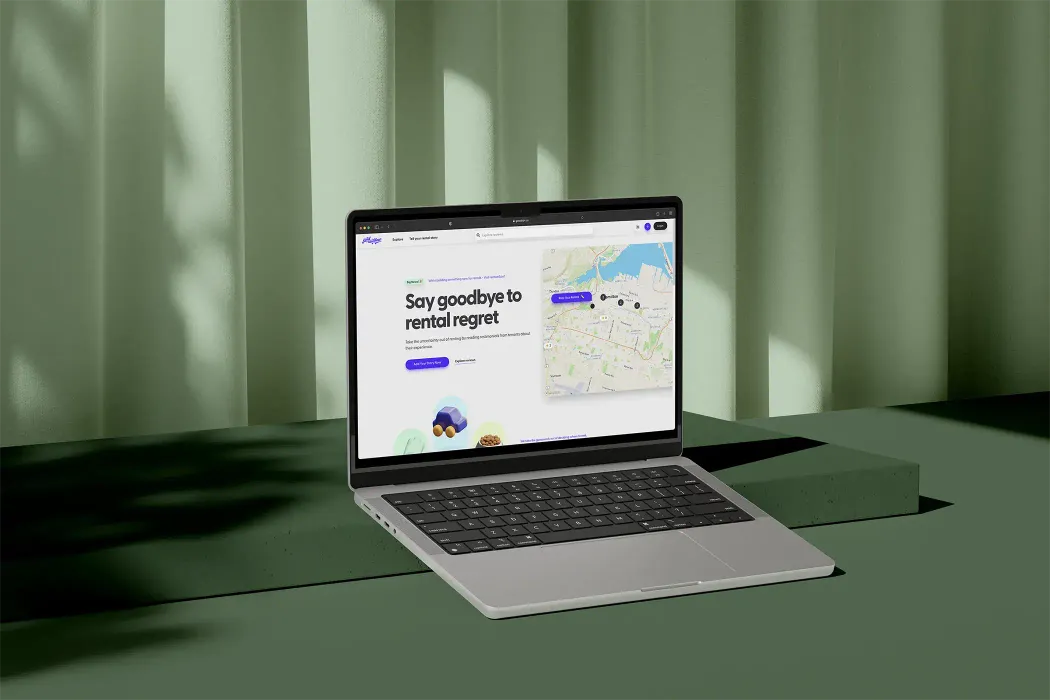 Laptop displaying a website with a tagline 'Say goodbye to rental regret' and a map interface, placed against a soft green background with curtains.