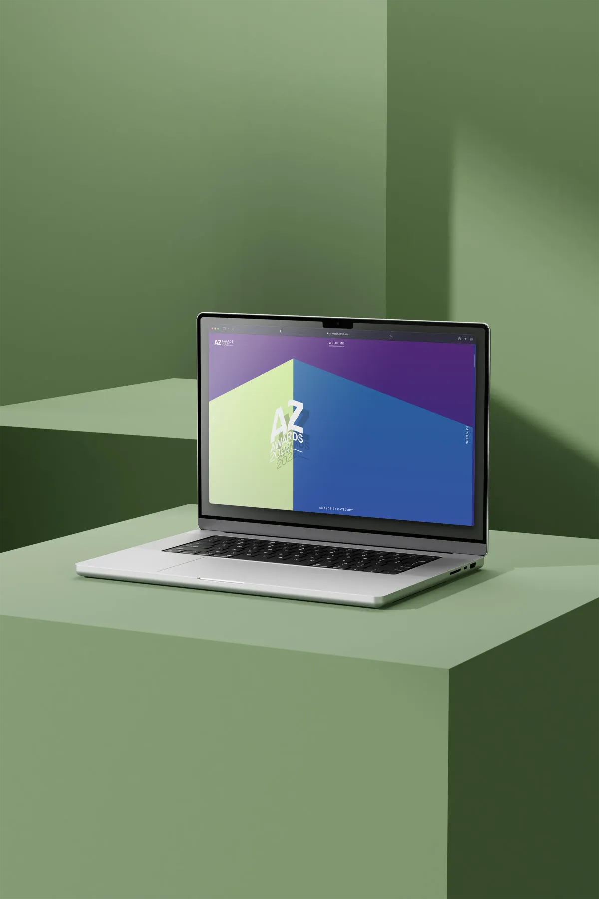 Laptop displaying a colorful webpage for the AZ Awards 2022, set against a soft green geometric background.