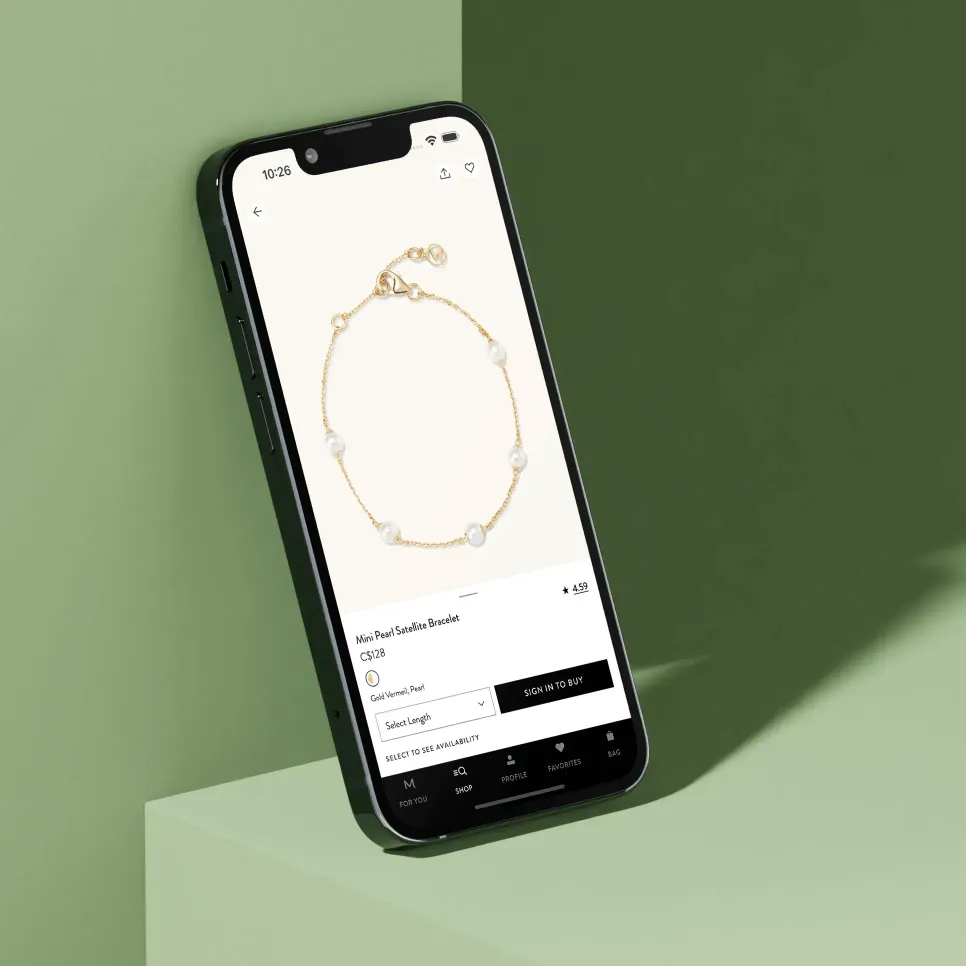 Smartphone displaying a product page for a Nini Pearl Satellite Bracelet priced at $128, against a soft green background.