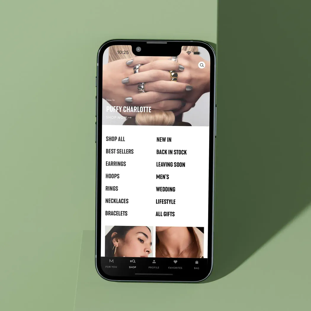 Smartphone displaying an online jewelry shop menu with categories like 'Shop All,' 'Best Sellers,' and 'New In,' against a soft green background.