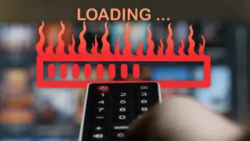 A remote control pointed at a TV screen, with a large red loading bar surrounded by flames and the text ‘LOADING …’ above it. The background is blurred, highlighting the frustration often associated with slow loading times.