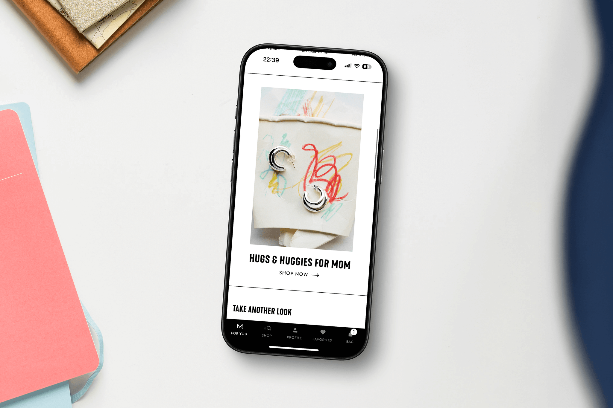 A person holding an iphone that's displaying the Mejuri App on the For You tab